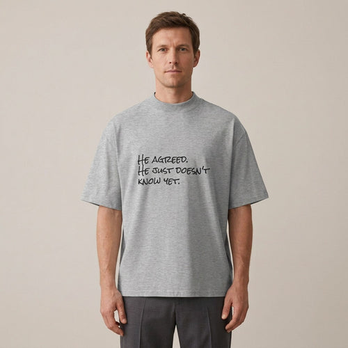 Model wearing the He Agreed. He Just Doesn't Know Yet. t-shirt in heather grey